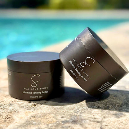 Two Sea Salt Body tanning butter jars balanced by poolside with lush green background