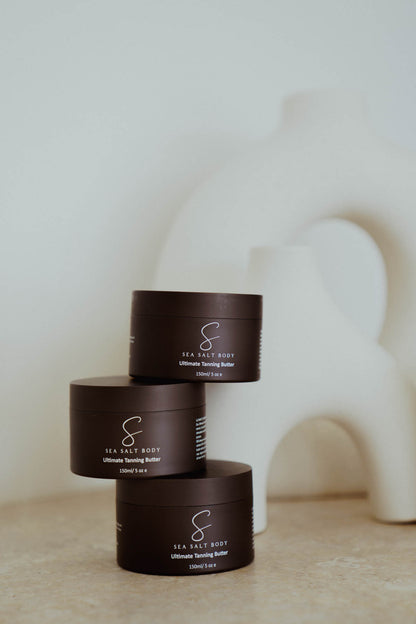 Three Sea Salt Body tanning butter jars stacked with modern white sculpture backdrop