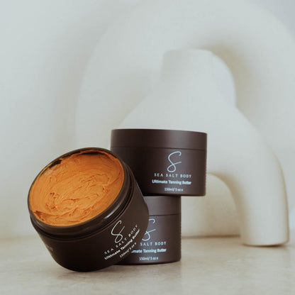 Open jar of Sea Salt Body Ultimate Tanning Butter with sculptural white background